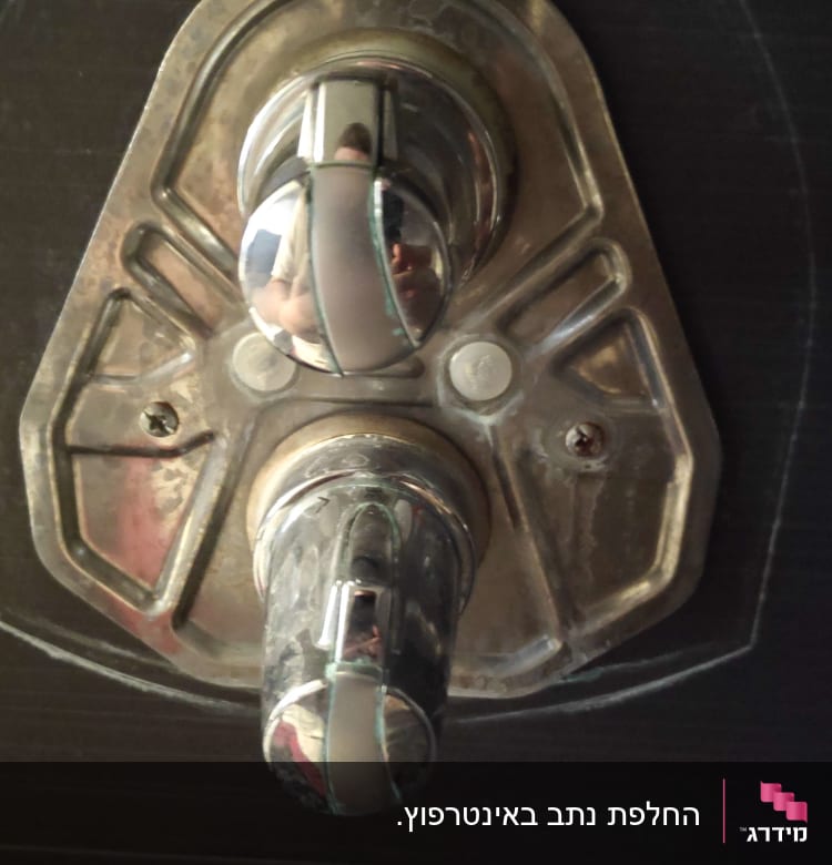 ברז מתכת עם ידיות עגולות על קיר